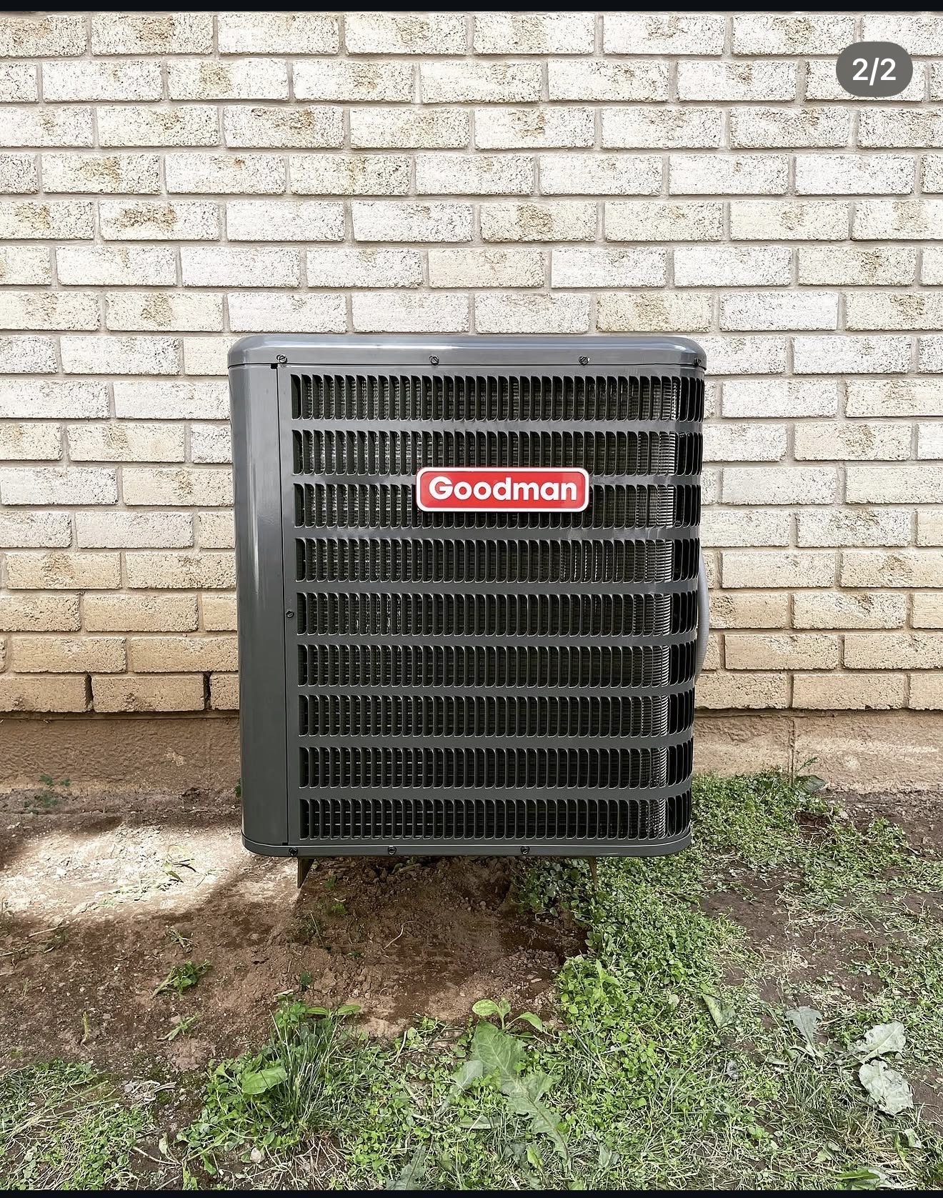 New Goodman air conditioner installed beside a brick home