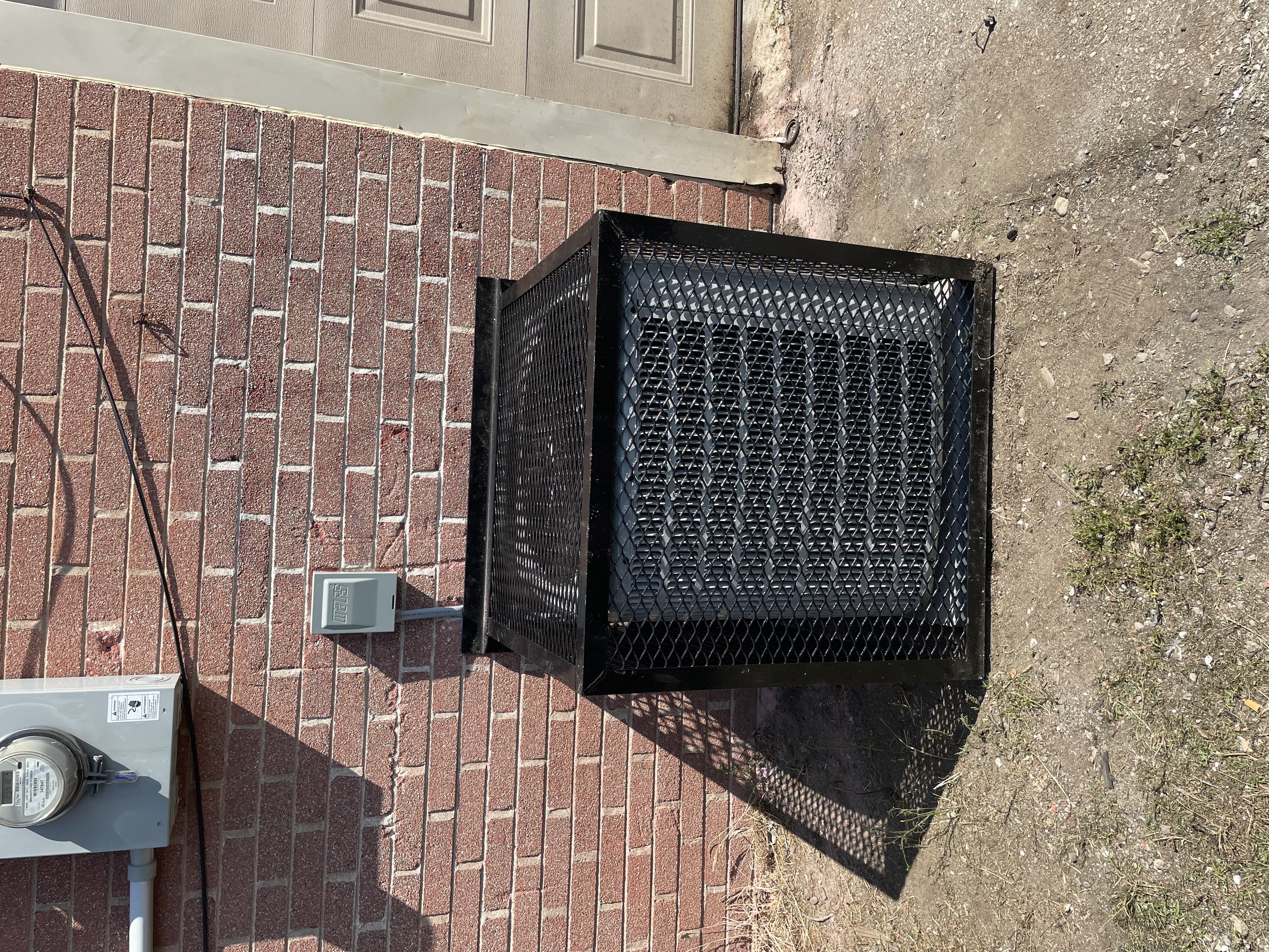 Outdoor central air condenser installation by a brick wall
