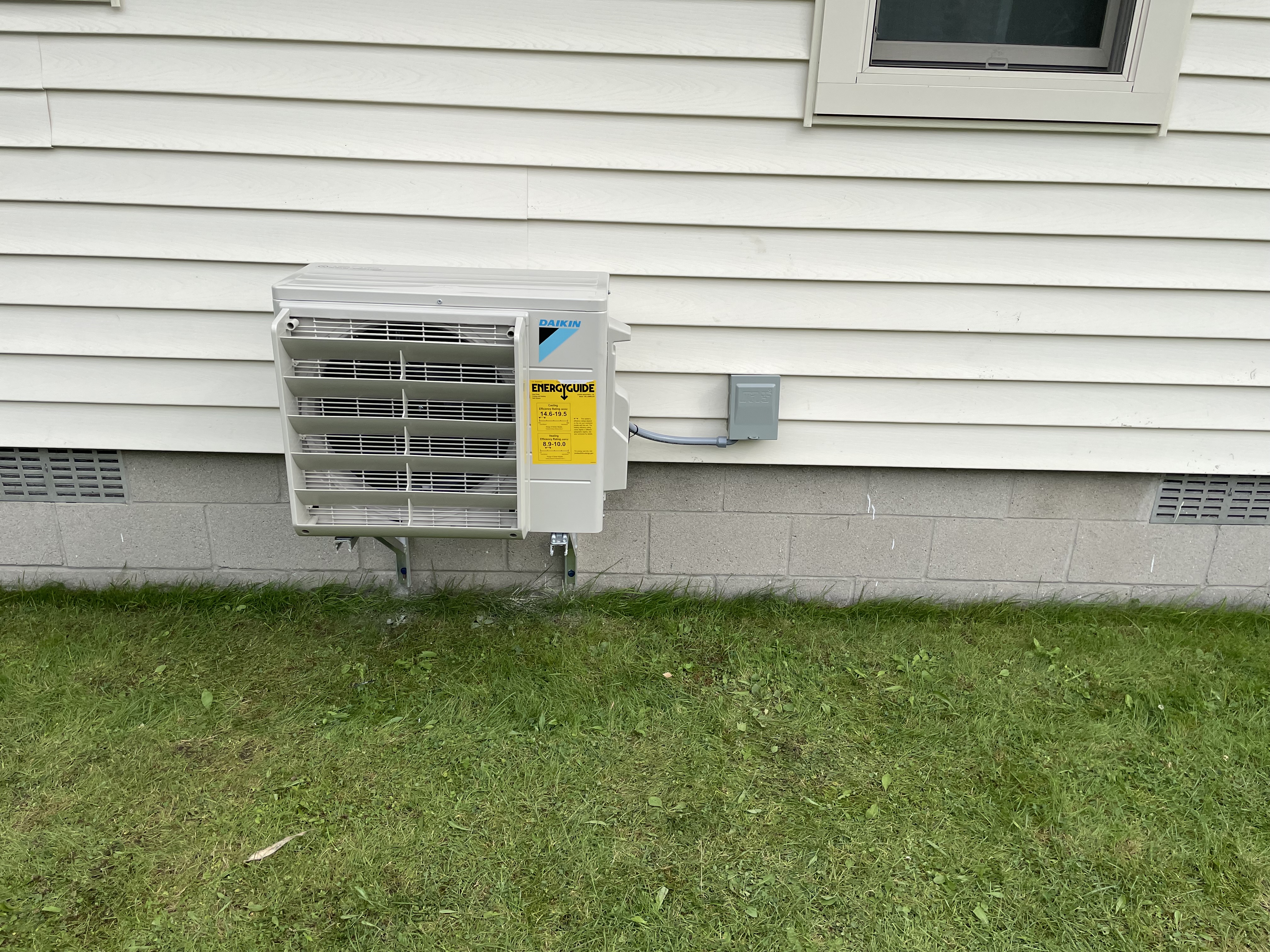 Compact condenser and line cover installed on white siding