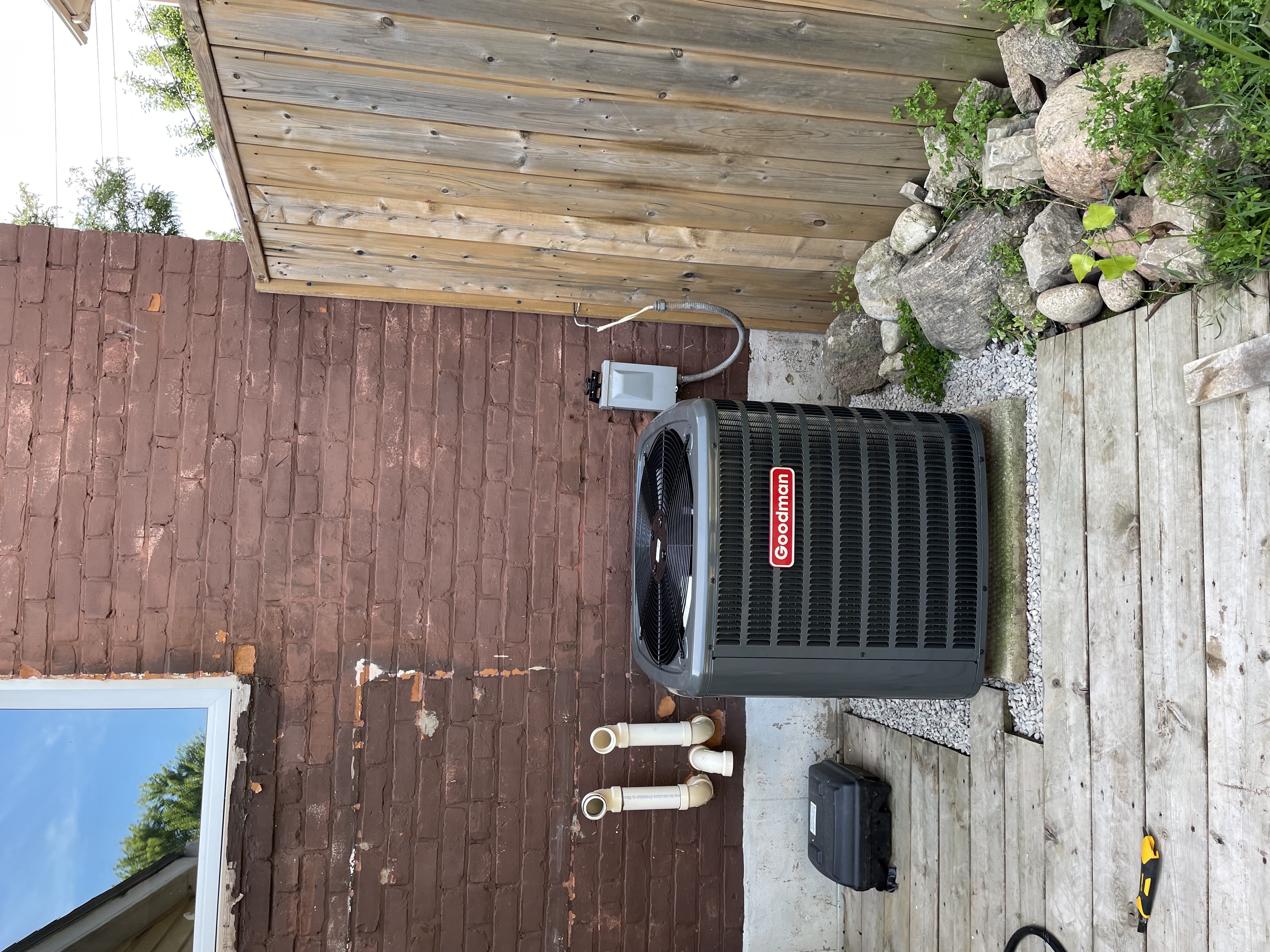 Central air condenser installed beside a brick home